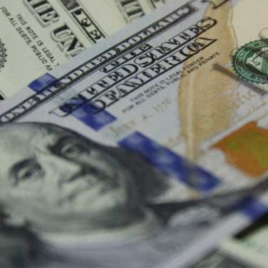 Close-up of U.S. one hundred dollar bills with Benjamin Franklin's portrait in focus, displaying intricate security features and design details, alongside exclusive cannabis seed promos.